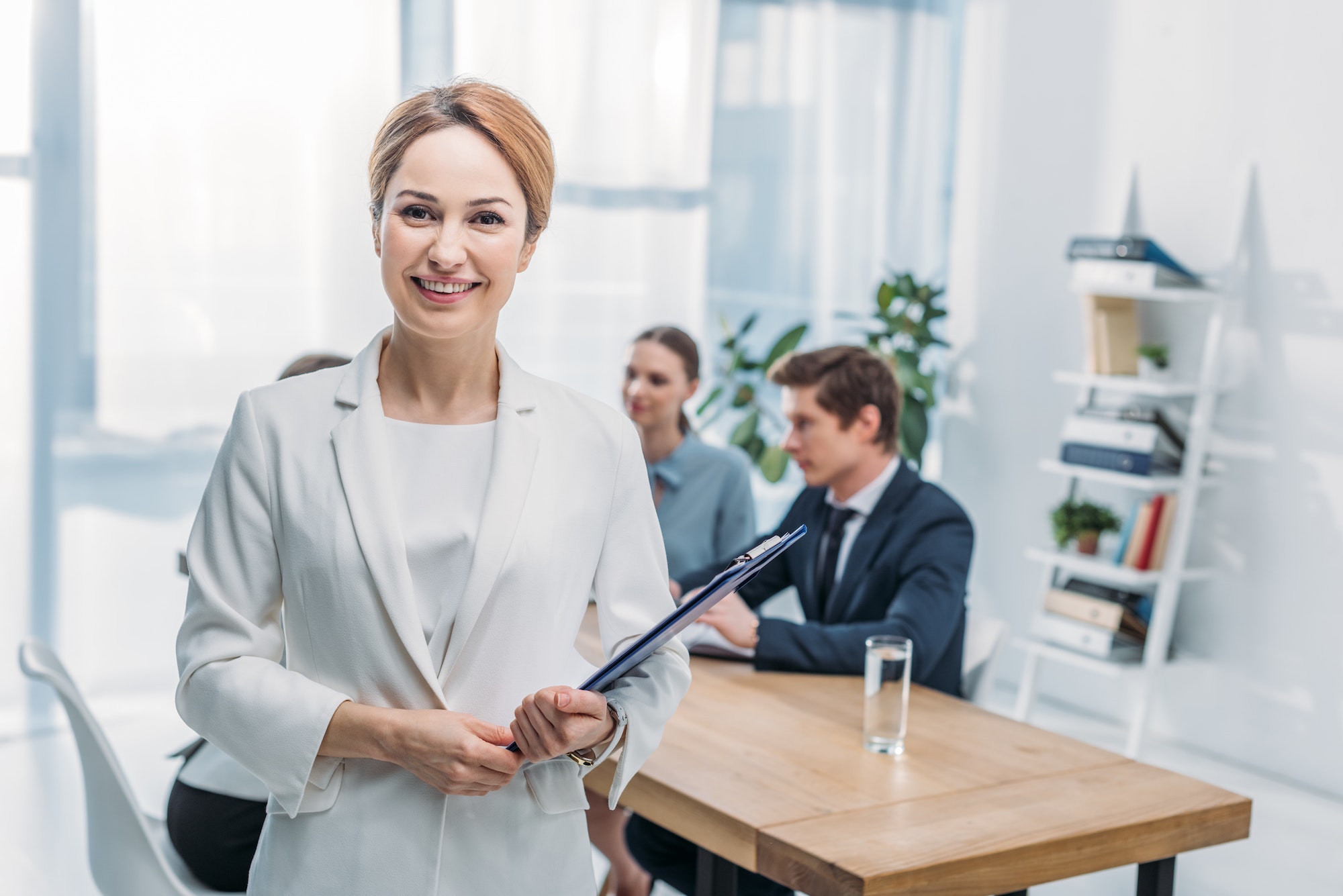 selective-focus-of-cheerful-recruiter-standing-with-clipboard-near-coworkers.jpg